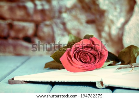 Book with a rose on top of an antique table in blue