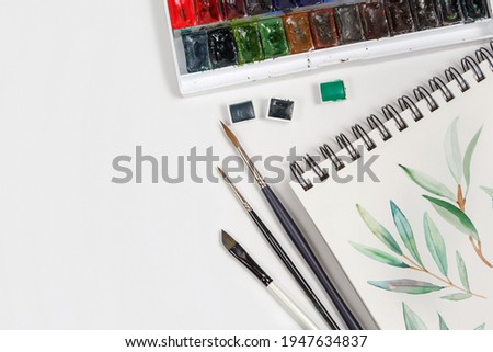 Drawings, brushes, palette and watercolor paints top view. Workplace of artist