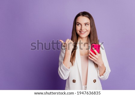 Close up portrait of lady hold phone look side direct finger empty space wear formal suit posing on purple wall