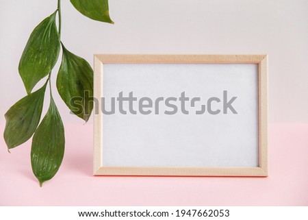 blank wood frame for notes on light background with green leaf