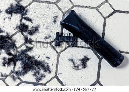 Electric hair clipper and cut hair on the floor. Self-haircut head and beard