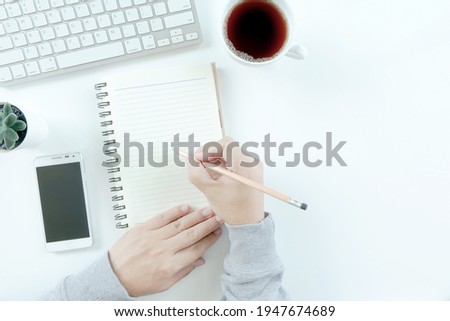Businessman wonking in modern white office desk table with laptop computer, smartphone with black screen over a notebook and cup of coffee. Top view with copy space, flat lay.