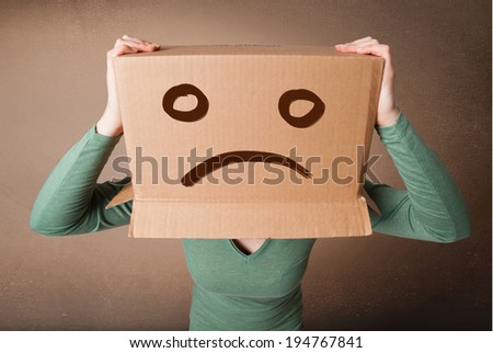 Young girl standing and gesturing with brown cardboard box on her head with sad face