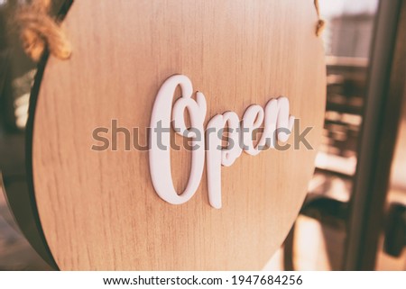 The wooden sign with text: Open hanging on the door in cafe