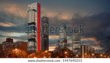 On cloudy gloomy sunset sky background illuminated with lights Cuatro Torres Four Towers Business Area night city view, district located in Paseo de la Castellana. Madrid, tallest skyscrapers in Spain