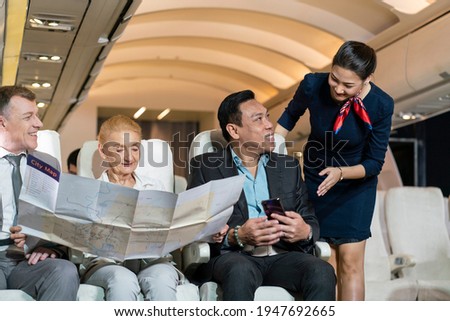 Flight attendants provide services to passengers, businessmen and female travelers on board during their flight journeys.  Royalty-Free Stock Photo #1947692665