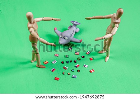 two wooden mannequins opening arms towards each other with flags of the world and colorful positive words between them