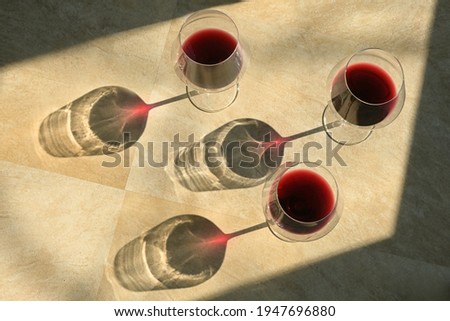 Three Glasses Of Red Wine and Shadow on Stone Table