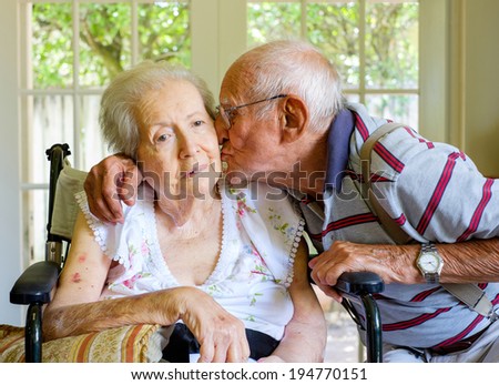 Elderly eighty plus year old woman in a wheel chair in a home setting with her husband. Royalty-Free Stock Photo #194770151