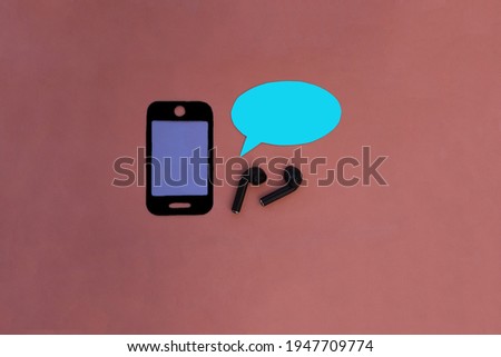 Mobile phone, wireless headphones in black, oval for text in blue on a pink background. Listening to sounds, modern technologies.
