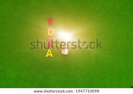 Electric light bulb, the word idea on a green background. Creativity, smart thoughts.