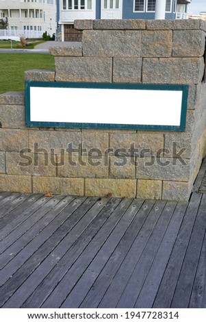Blank white sign with a green border on a stone wall