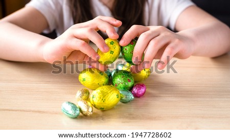 Easter candy eggs in children's hands. Wooden background, close-up