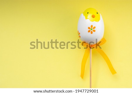 Colorful Easter egg chick on yellow pastel background