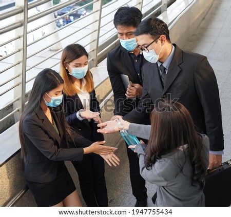 Group of Business people wearing medical protective face mask cleaning their hands with gel hand sanitizer before working, health care and medicine concept.                           