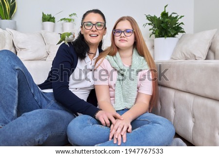 Friendly cheerful family, portrait of mom and teenage daughter, with green parrot