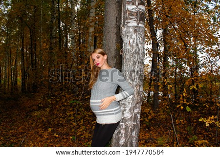 Pregnant Girl near birches in the forest in autumn