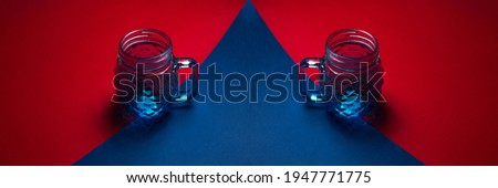 Panoramic photo of glass mug's for juice on two textured backgrounds of red and blue colors.