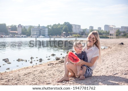 Happy family, mother with three sons resting in the beach with fruits, people dressed in t-shirts