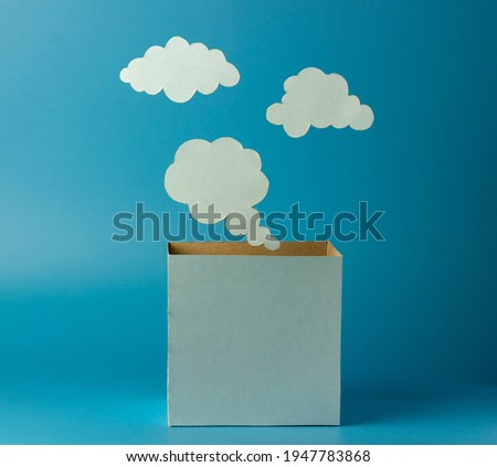 Think outside the box. Boxes and clouds or thoughts from paper on a blue background. Creative thinking concept.
