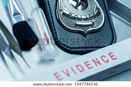 Police badge next to tools in crime lab, conceptual image