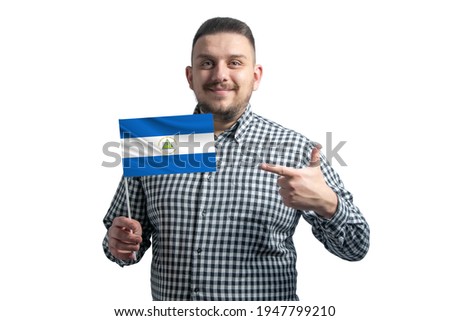 White guy holding a flag of Nicaragua and points the finger of the other hand at the flag isolated on a white background.