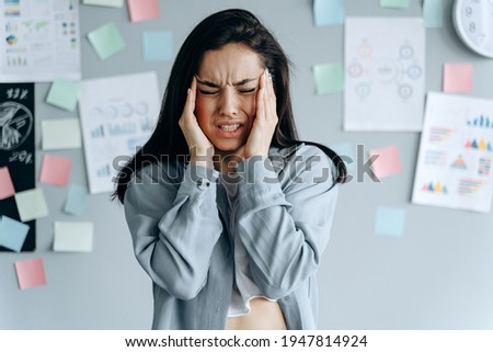 Tired stressed businesswoman feeling strong headache massaging temples exhausted from overwork, fatigued overwhelmed lady. Executive worker suffering from pain in head or chronic migraine in office Royalty-Free Stock Photo #1947814924