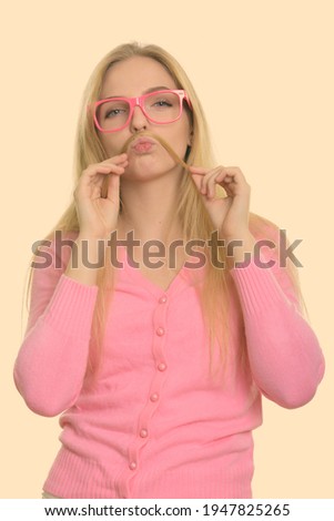 Studio shot of young beautiful teenage girl playing with her hair as mustache
