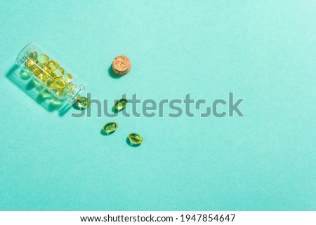 Omega-3 tablets in an old bottle on a turquoise matte background. Healthy life concept, prevention of various diseases. Trendy hard light, dark shadow, flat lay, mockup, template, top view