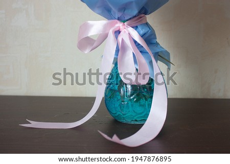 pink bow on a bouquet in a blue glass vase on the table