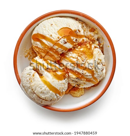 bowl of caramelized walnut and maple syrup ice cream scoops decorated with caramel sauce and cookie crumbs isolated on white background, top view