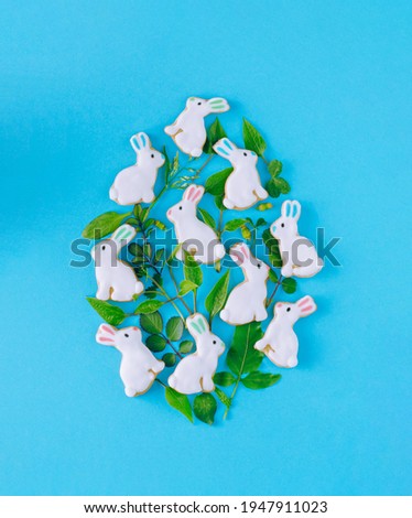 Easter creative concept. Egg shape made of green flower and minila rabbit. Blue background.