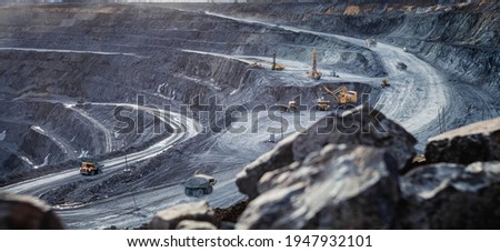 Work of heavy equipment in an open pit for gold ore mining, soft focus Royalty-Free Stock Photo #1947932101