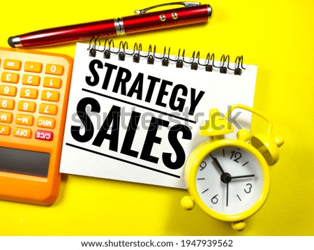 Selective focus of calculator,pen and clock with text STRATEGY SALES on yellow background.Business concept.