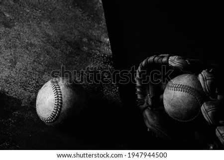 Old used baseball equipment still life with dark low key lighting in black and white.