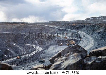 Work of heavy equipment in an open pit for gold ore mining, soft focus Royalty-Free Stock Photo #1947945640