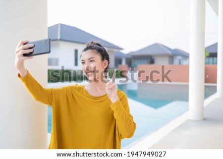 Asian woman taking a selfie with a swimming pool