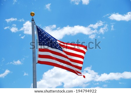 American flag floating in the wind with a blue sky in the background
