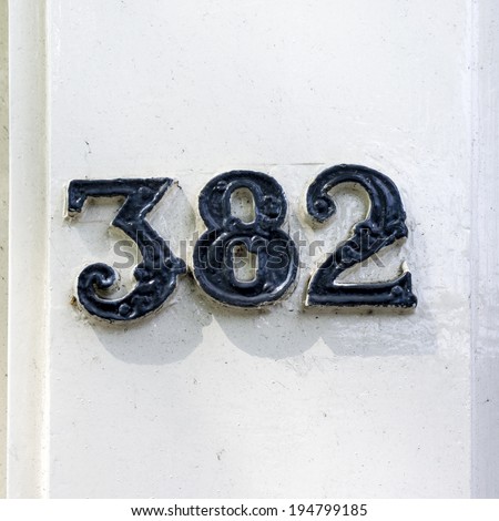 house number three hundred and eighty two. Relief lettering on a white painted doorpost