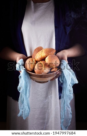 Homemade baked patties on a clay bowl in the hands of a woman