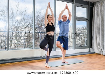 Girl and mature man practice yoga together