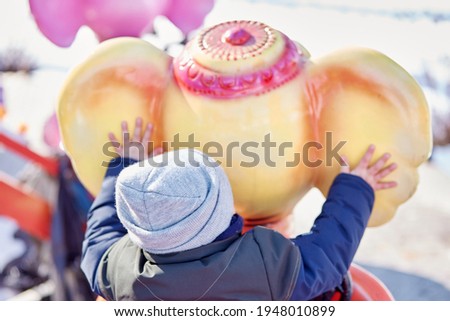 Boy on a carousel in early spring. Child activities concept. Happy childhood