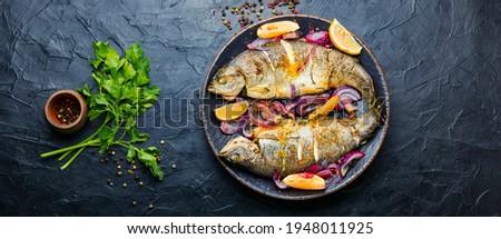 Roasted trout with lemon and onion on plate.Grilled trout Royalty-Free Stock Photo #1948011925