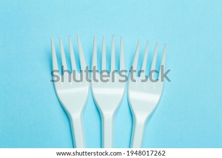 Plastic forks on a blue background. Plastic waste and pollution concept.
