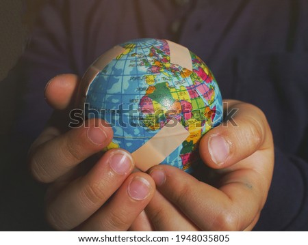 Natural Hands of a boy holding a Globe full of bandages. Global warming, Climate change, Environmental problems. World pollution, Earth day, April 22. Royalty-Free Stock Photo #1948035805