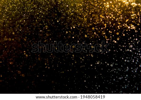 Gold bokeh of lights from water on black background