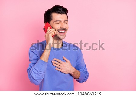 Photo of charming funky young man laugh joke talk hold phone isolated on pastel pink color background