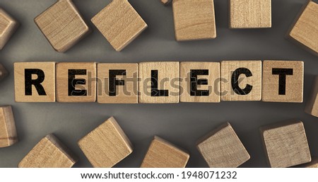 The word REFLECT on small wooden blocks at the desk. Conceptual photo. Top view
