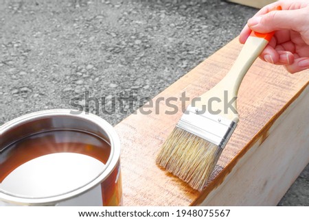 Painting a garden product made of wood with paint and varnish. Home hobby, DIY. Outdoor paint coating. Royalty-Free Stock Photo #1948075567