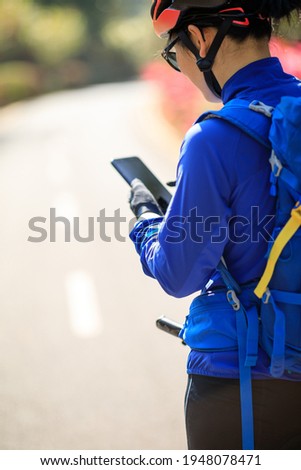 Cyclist use smartphone when riding mountain bike on forest trail